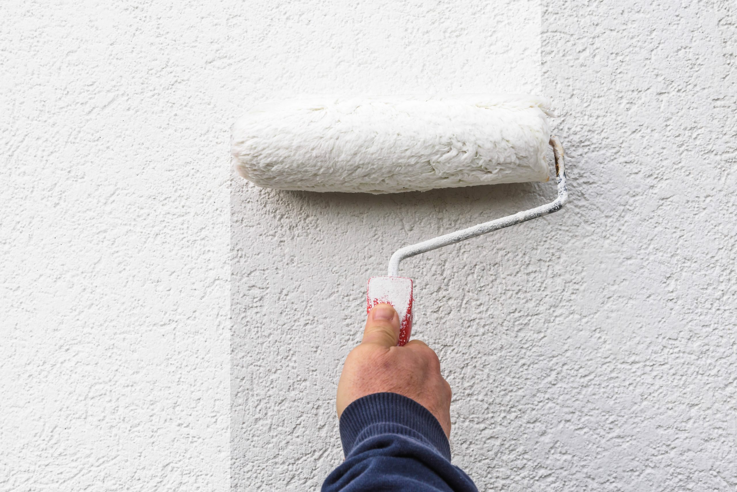 Image of hand holds paint roller and painting a wall, by Mirsad